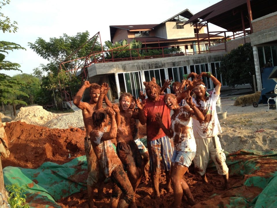 Mud-covered course group cheering at the end of a practical natural building day