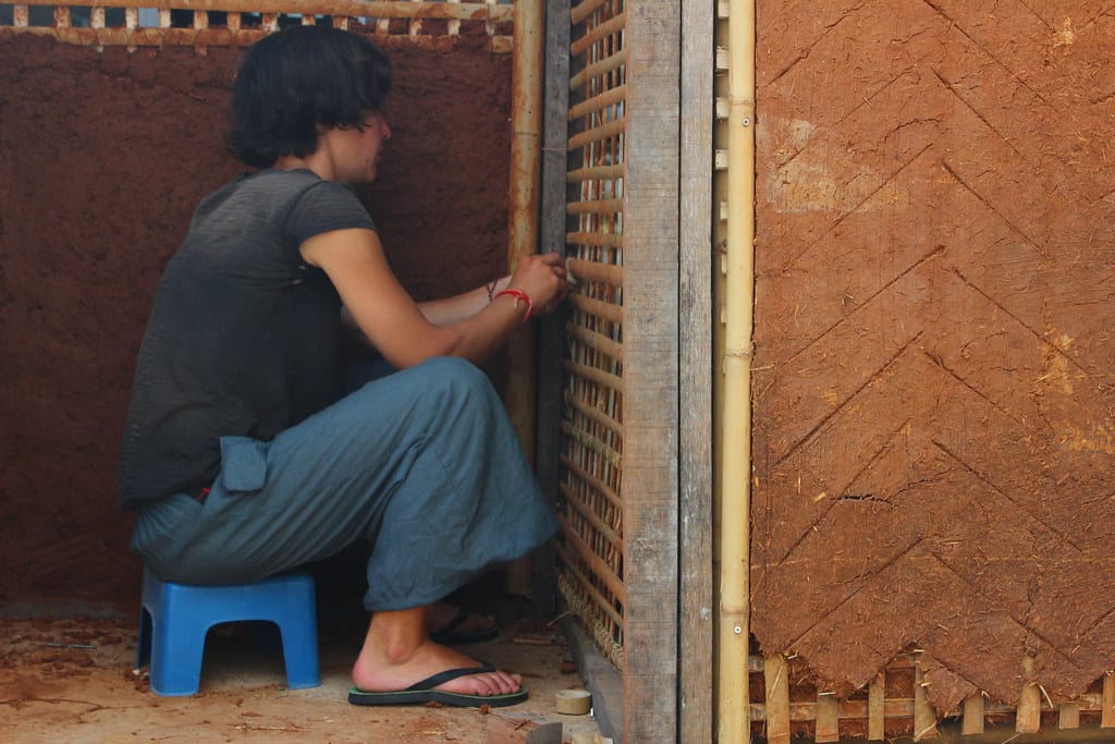 Course participant weaving a bamboo lattice wall panel set into an adobe wall corner