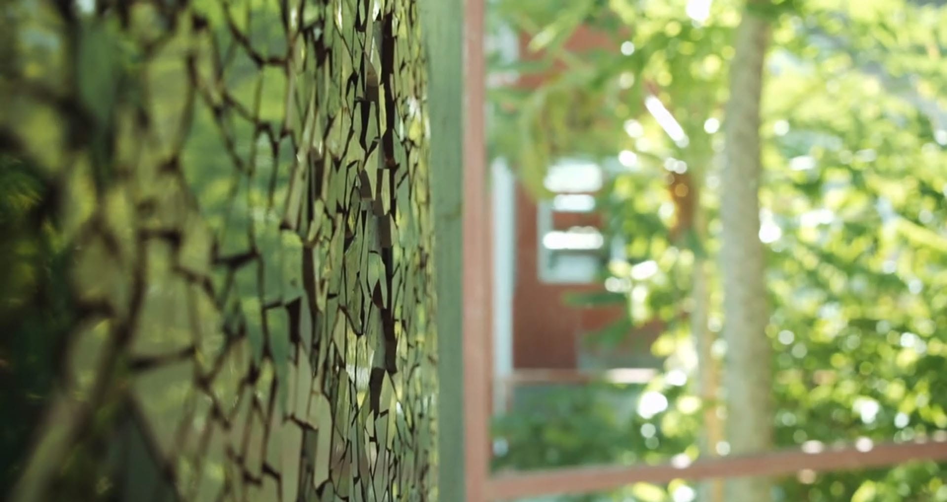 A weathered mosaic tile wall, cracked and softened by the seasons
