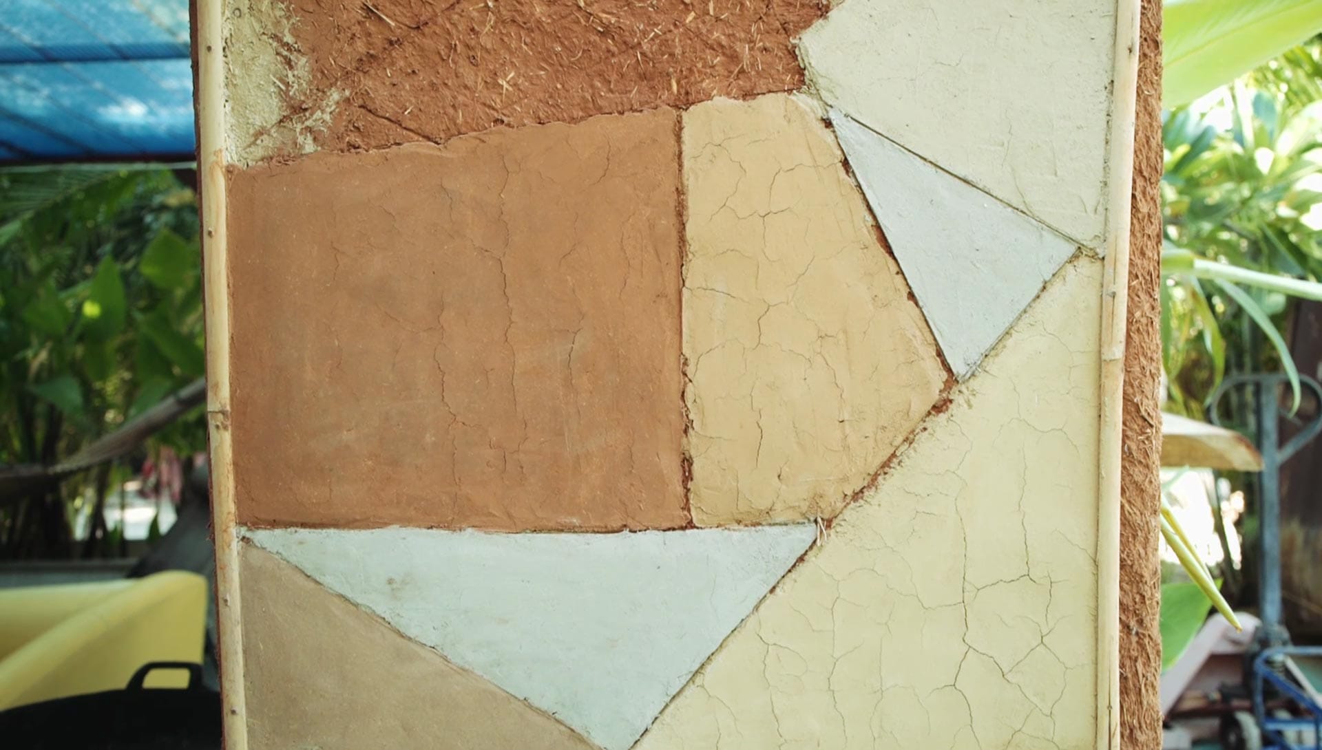 An adobe wall finished in a geometric patchwork of raw clay and pale plaster panels