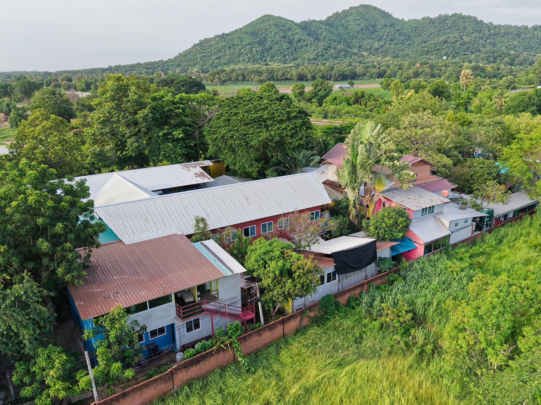 Aerial view of Mosaic School beneath the forested hills of Bang Phra