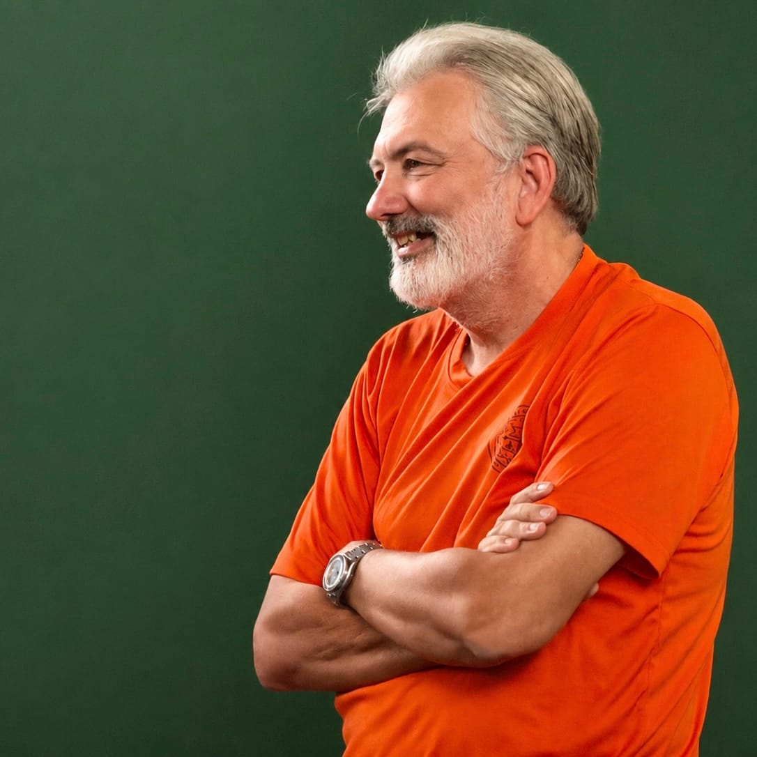 Neil Willmann, founder and permaculture teacher, smiling against a green background