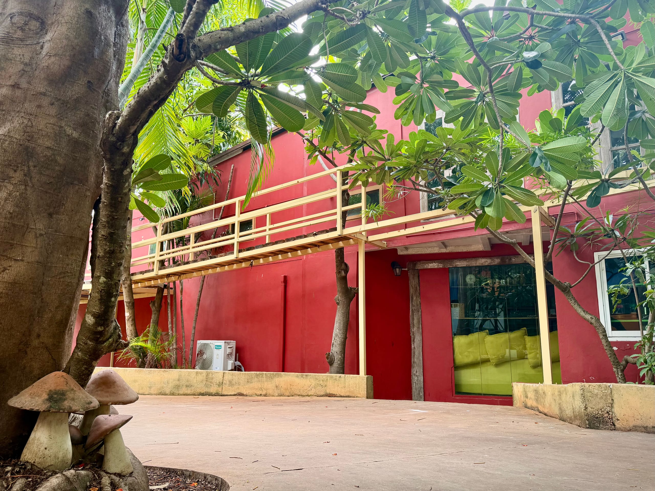 The red two-storey building at Daruma with its yellow-railed walkway, seen through the trees
