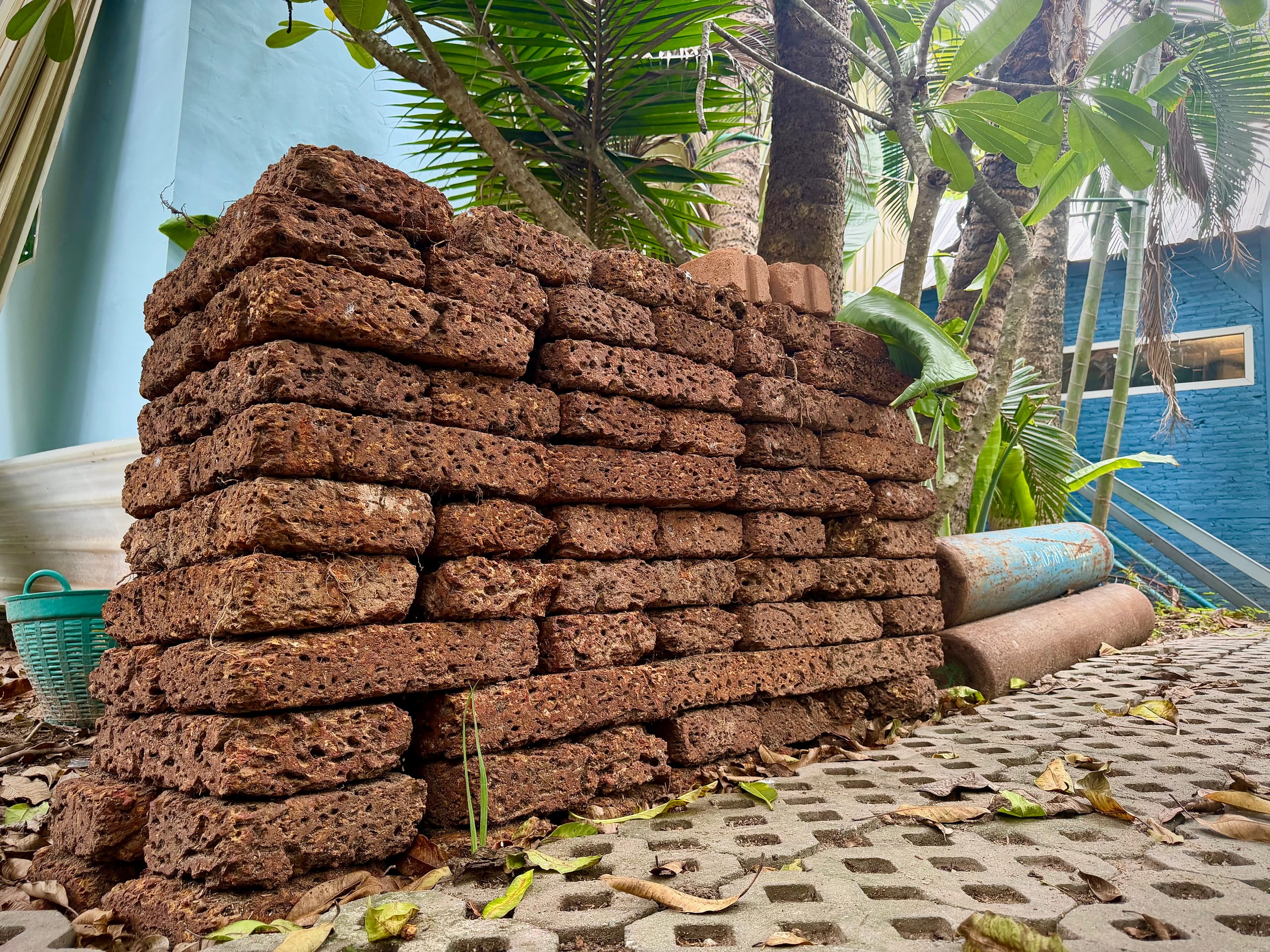 Laterite bricks stacked against a blue painted wall