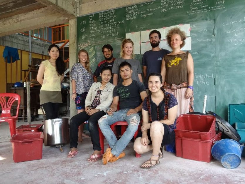 Nine course participants posing together in front of a chalkboard covered with handwritten notes