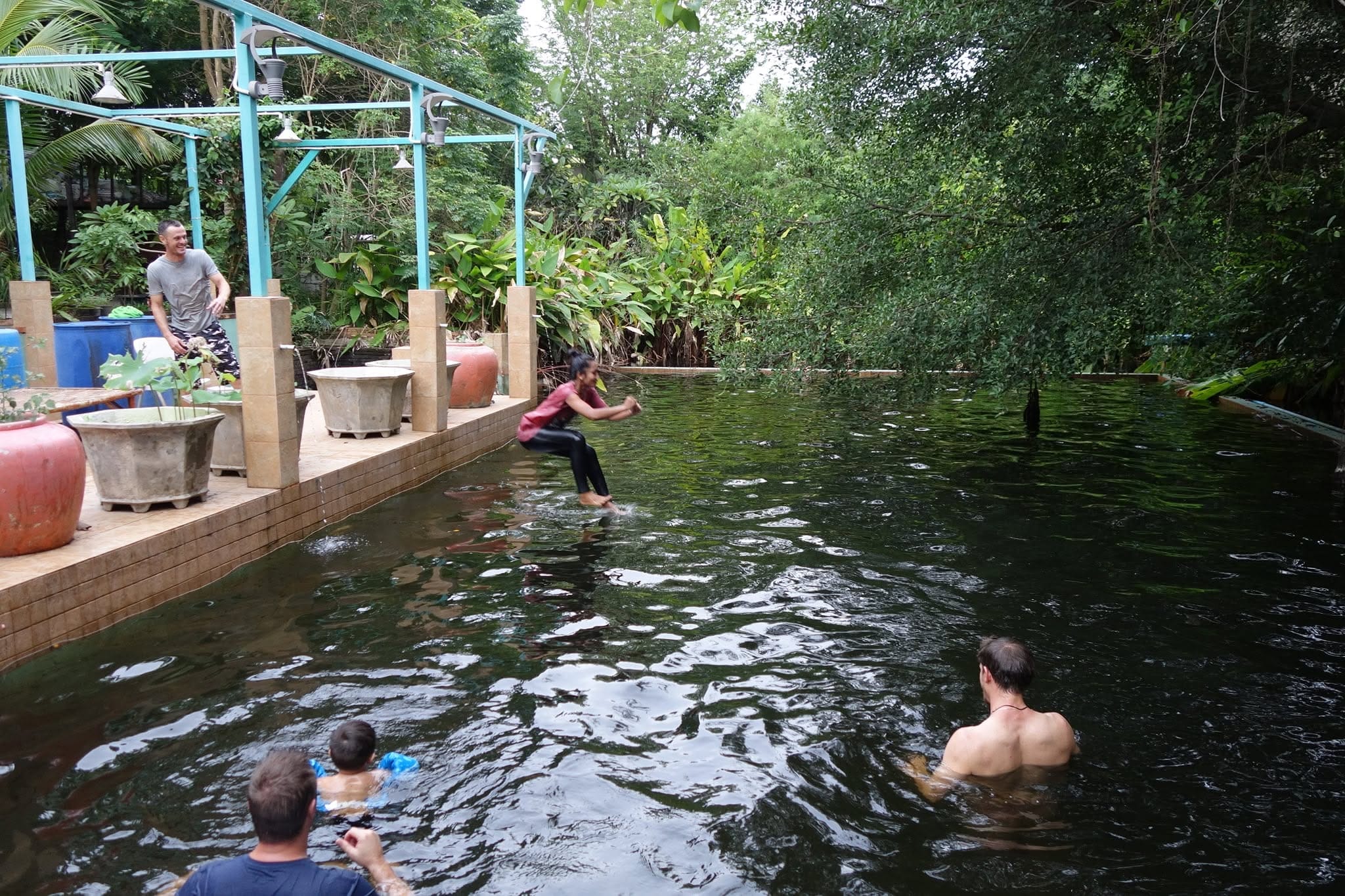 A girl leaping from the poolside deck into the natural swimming pond