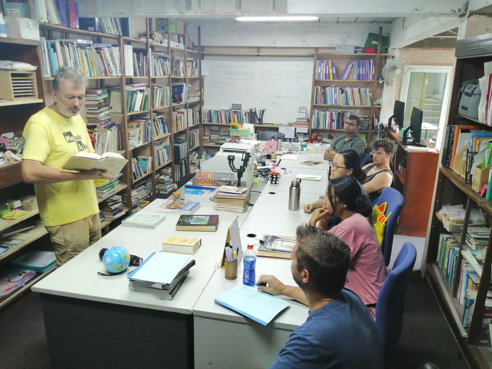 A Mosaic School teacher reading aloud to a group of seated students