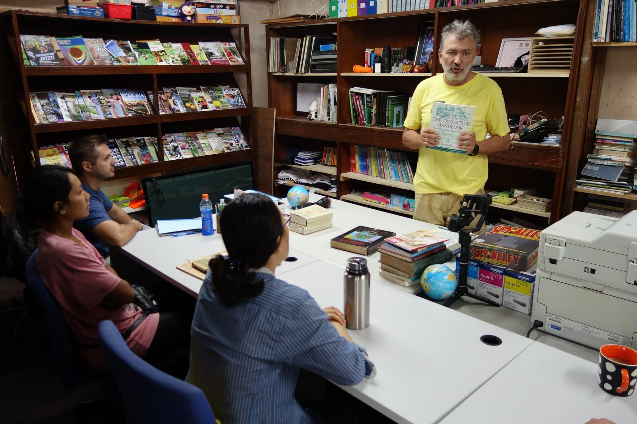 Neil holding a copy of The Transition Handbook while addressing a class