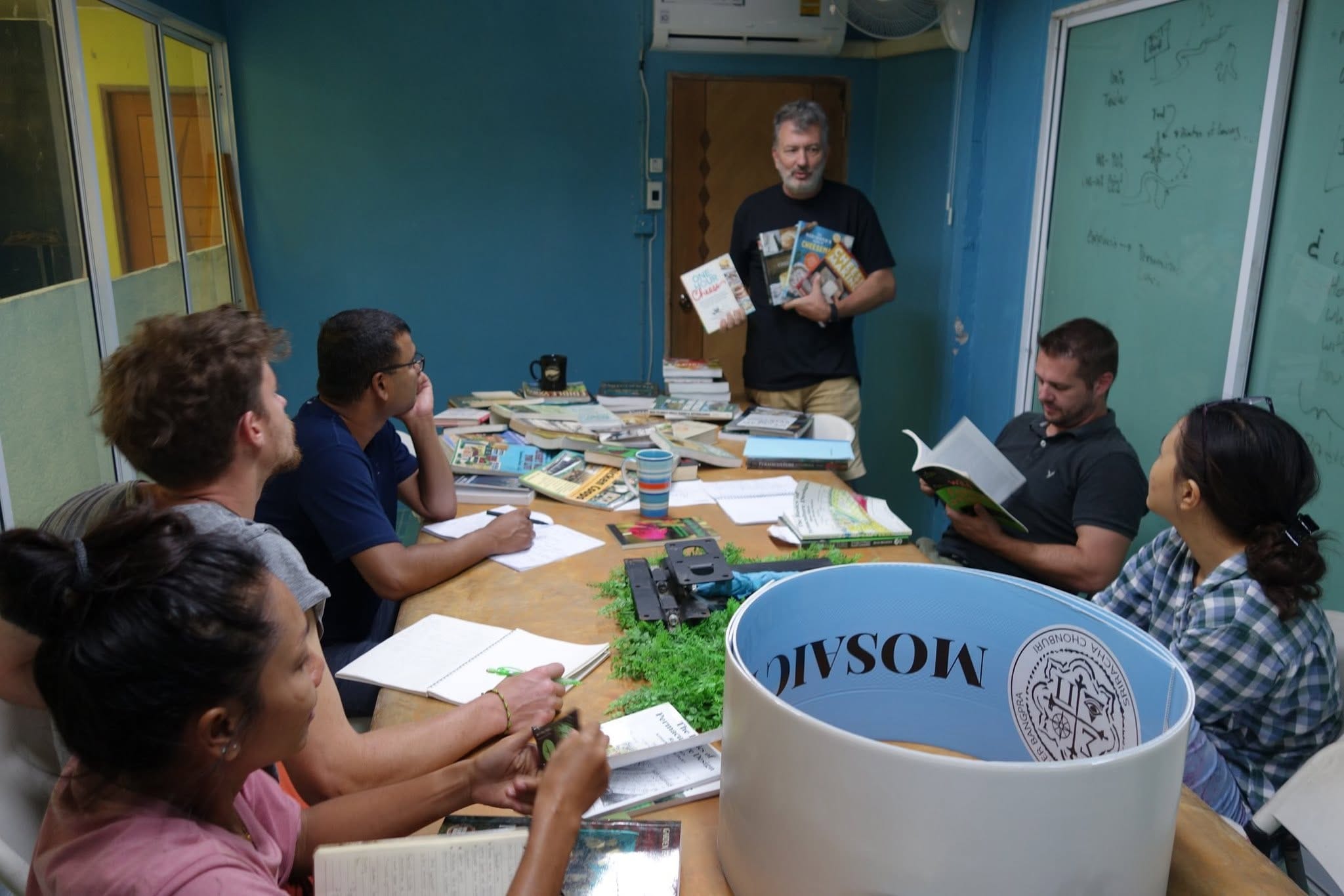 A discussion over a stack of cheese-making books in a blue-walled room at Daruma