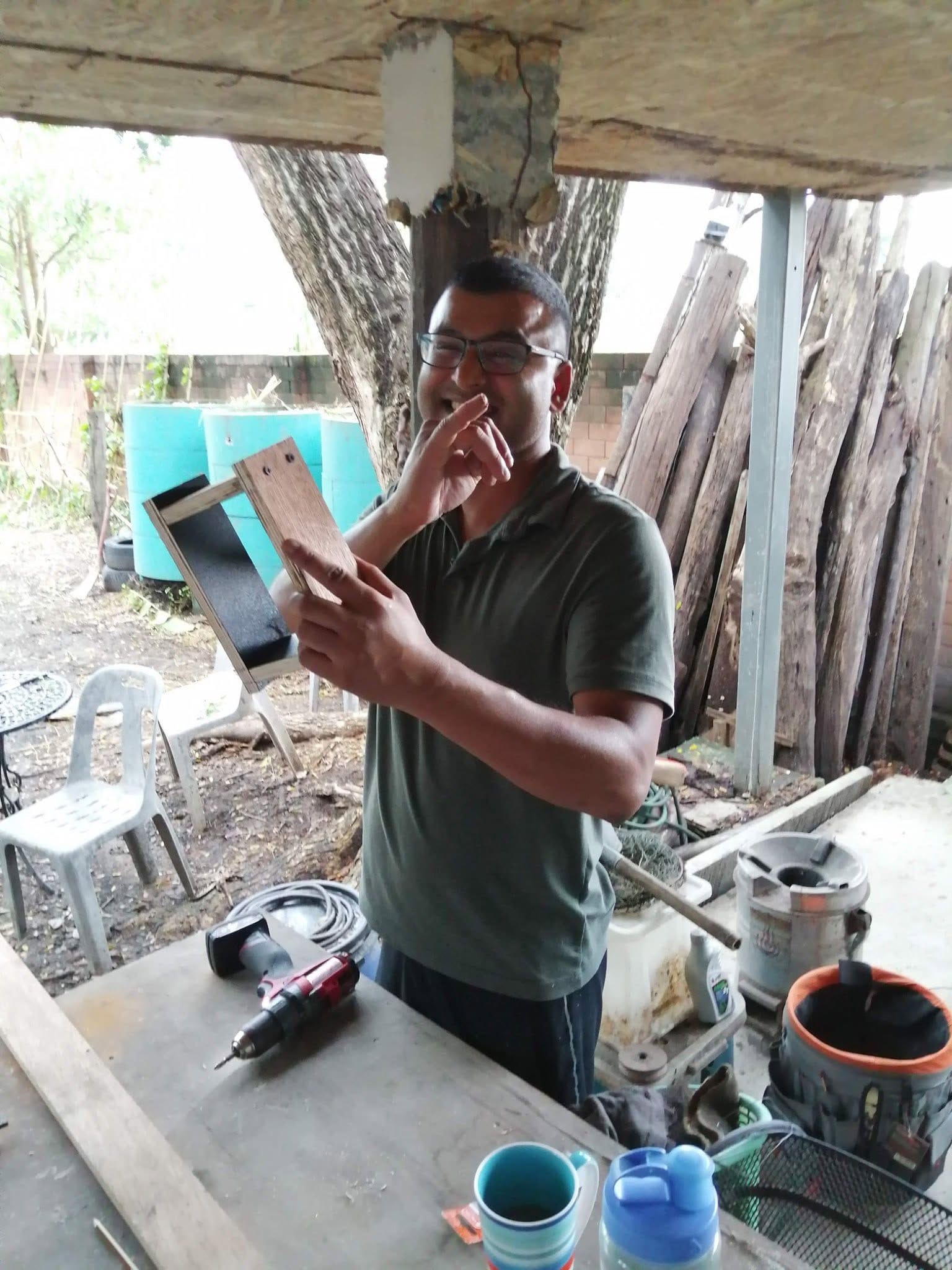 A smiling course participant holding up a small wooden frame in the workshop