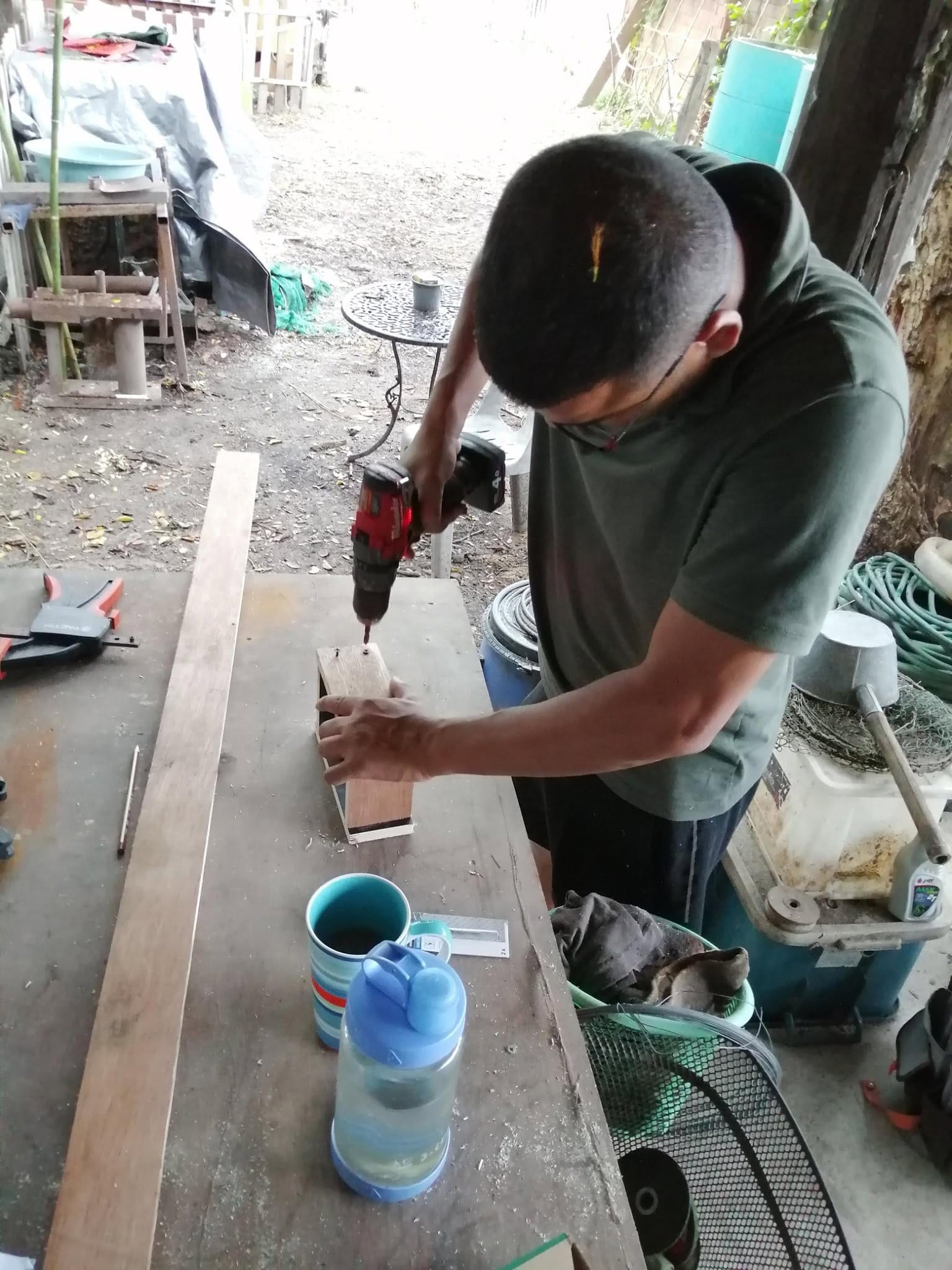 A volunteer using a cordless drill to fasten a wooden frame at a Daruma workbench