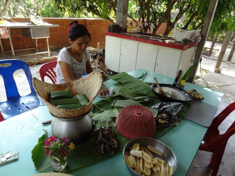 A volunteer wrapping banana leaf parcels in the farm kitchen