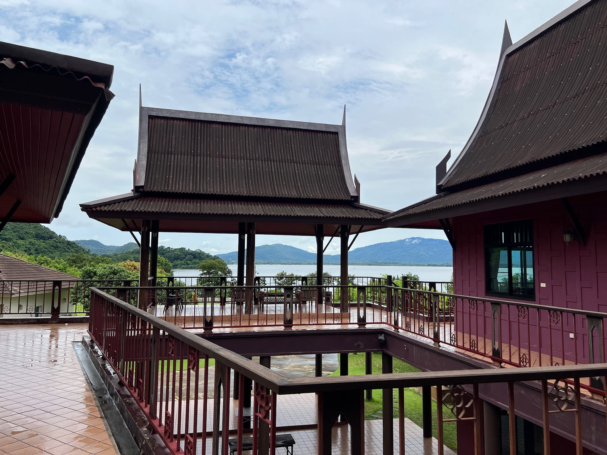 Upper terrace with steep gabled roofs and ornamental railings, looking out over the lake and forested hills.